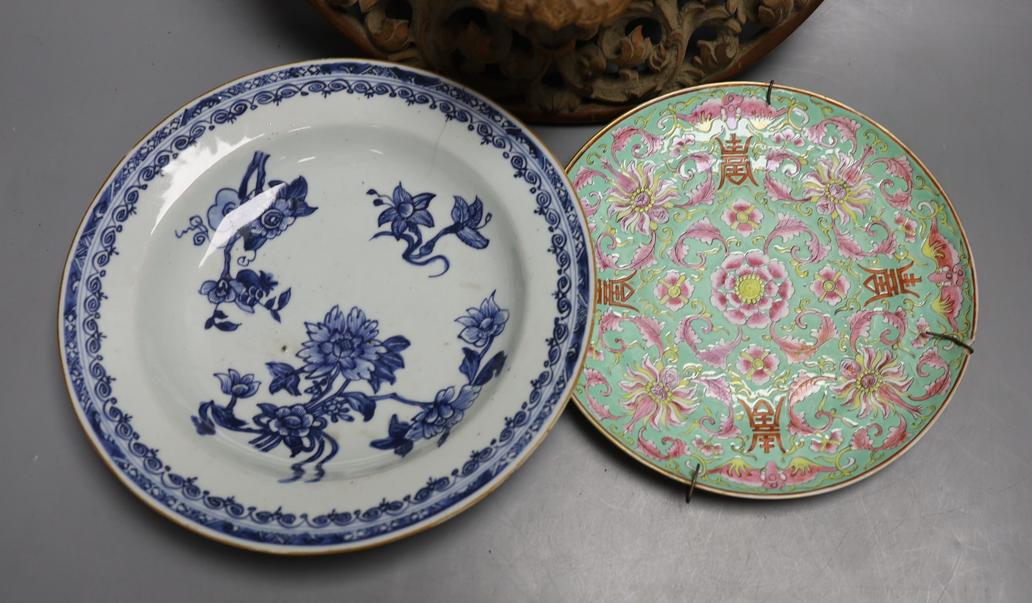 A Chinese blue and white plate with floral decoration, 23cm diameter, together with another plate and wooden panel relief of oriental figure (3)